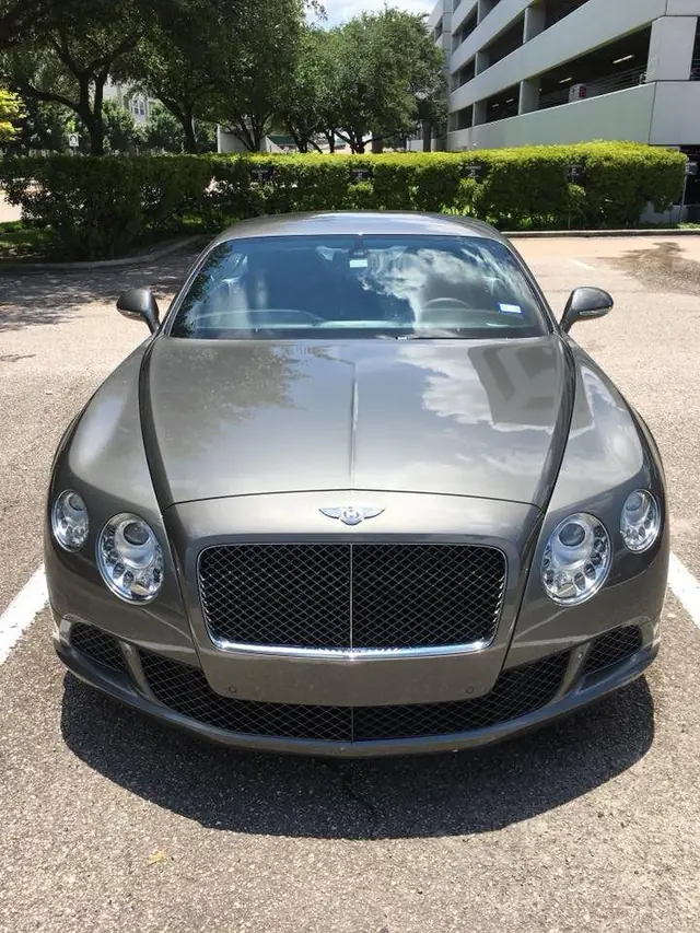A grey Bentley Continental GT detailed and parked in an office car park beside a multi storey parking structure